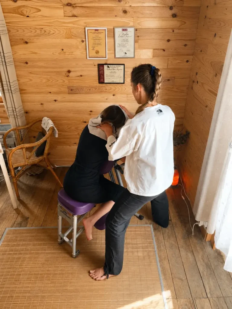 Gaëlle Chiariot pratiquant un shiatsu assis sur une chaise ergonomique dans son cabinet.
