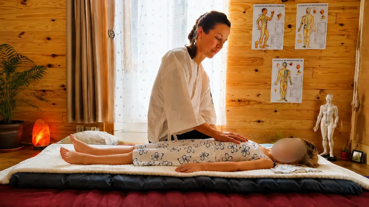 Gaëlle Chiariot réalisant une pression abdominale douce sur un enfant allongé sur un futon dans son cabinet de shiatsu.