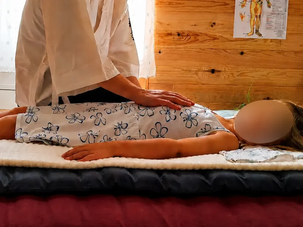 Praticienne en shiatsu posant les mains sur une personne allongée pendant une séance personnalisée