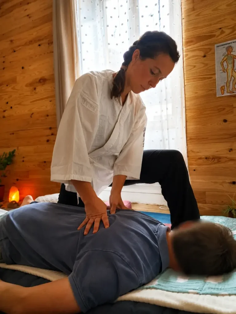 Gaëlle Chiariot réalisant une pression shiatsu sur le dos d’une personne allongée sur un futon.