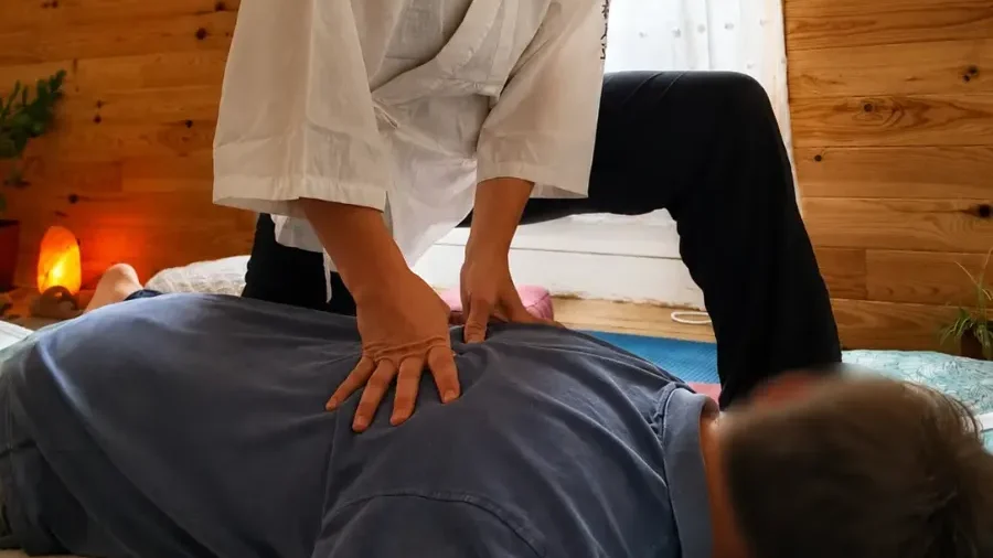 Gaëlle Chiariot réalisant une pression shiatsu sur le dos d’une personne allongée sur un futon.